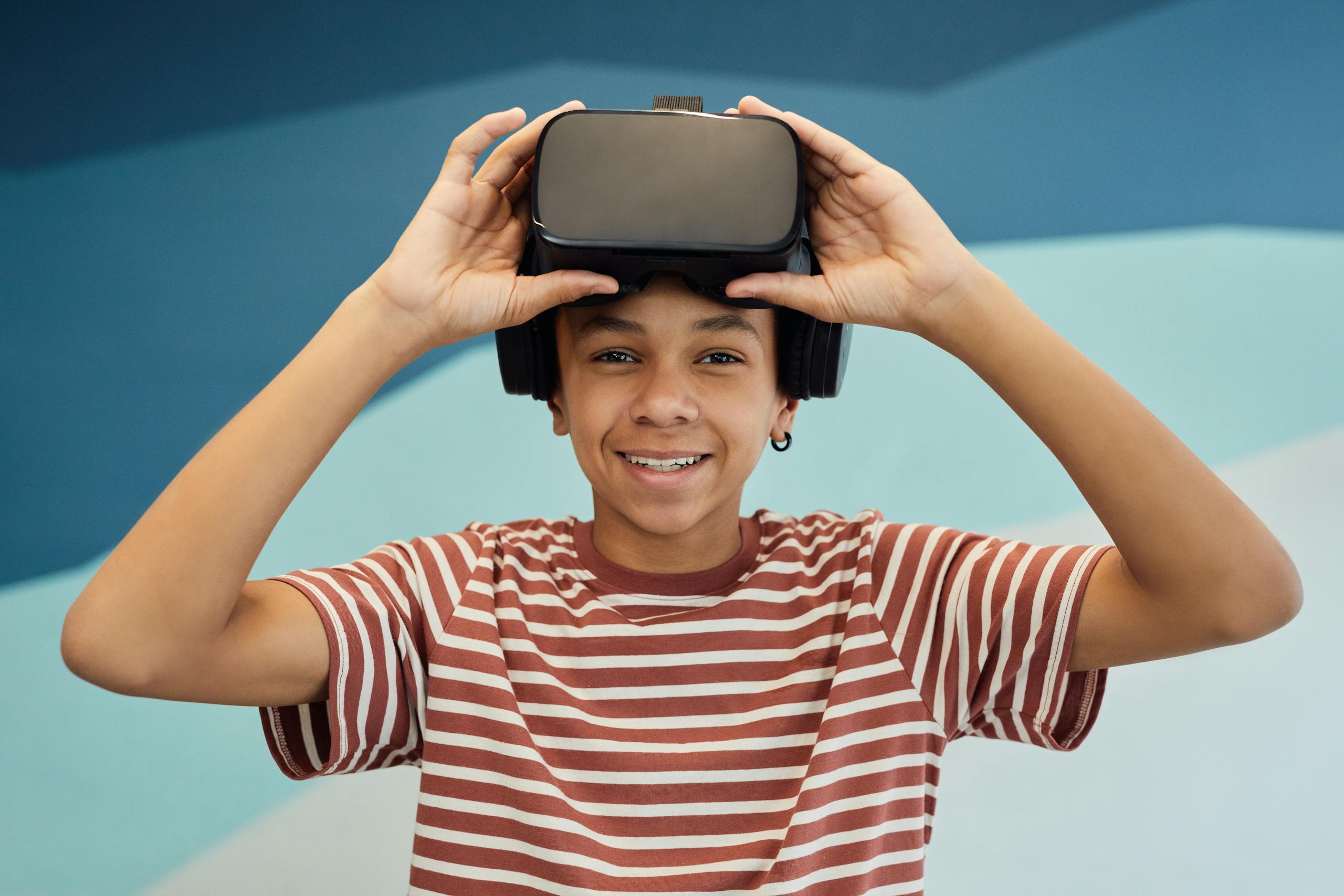 Smiling teen boy using a VR headset indoors, enjoying virtual reality technology.
